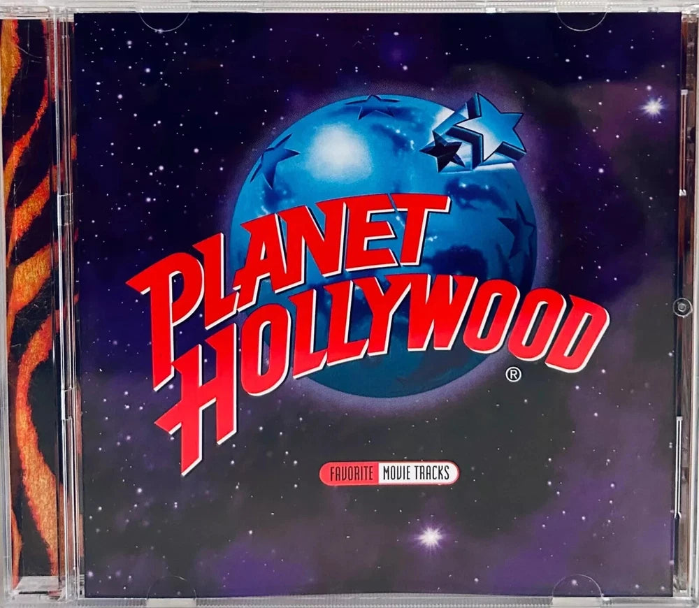 Planet Hollywood CD "Favorite Movie Tracks". The CD is in a jewel case. The cover features the Planet Hollywood logo with a blue planet and red lettering over a night sky. The side of the jewel case has a tiger stripe pattern.