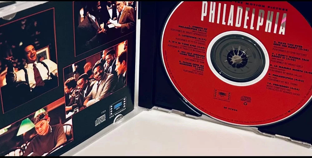 Open CD case of the "Philadelphia" movie soundtrack, featuring a red CD with track listings and images from the film on the case.