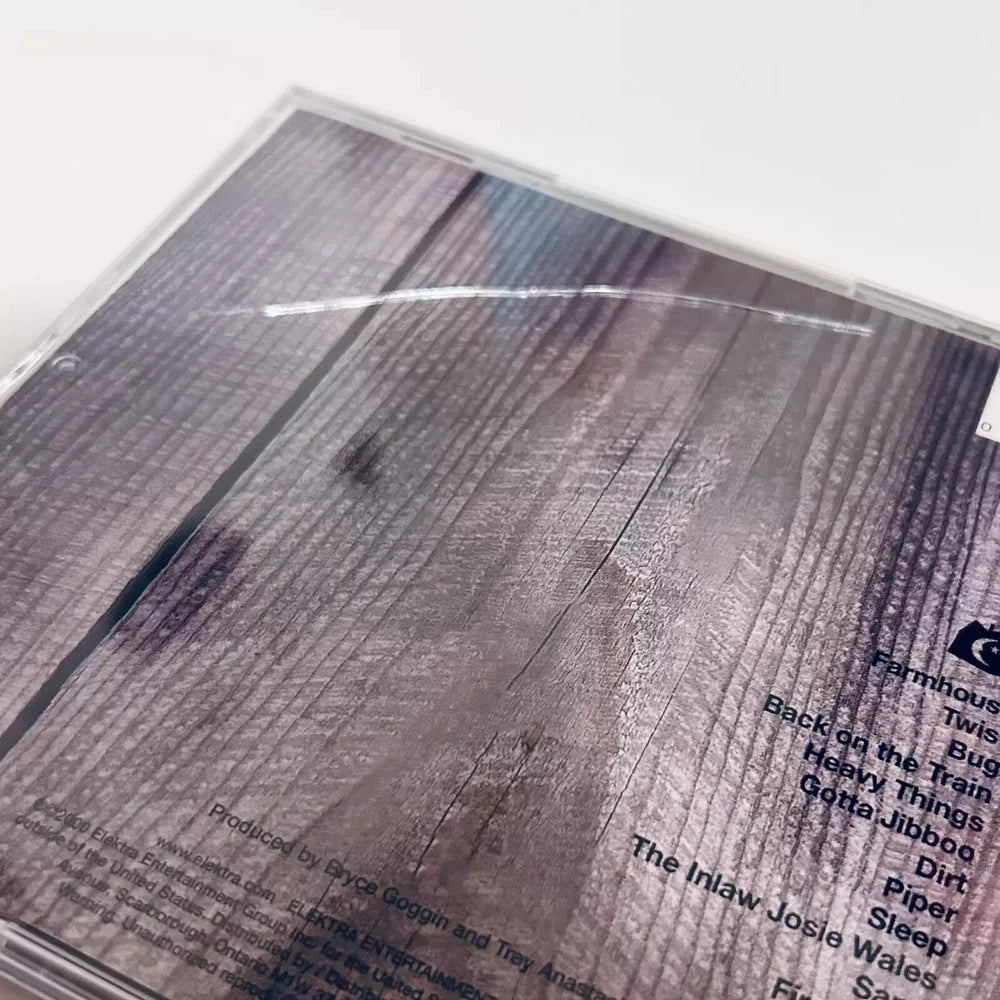 CD case of the band Phish's album Farmhouse, featuring a wood panel background with song titles and production credits.